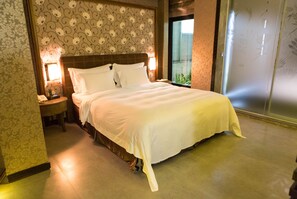 Quarto de hotel com uma cama grande, mesa de cabeceira com telefone e janela com vista para áreas verdes.