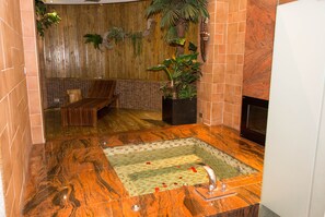 Casa de banho com parede de madeira, um banco, uma planta em vaso e chão em mosaico.