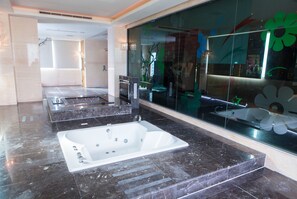 Un baño moderno con una bañera grande, una zona de ducha separada y una pared de vidrio con detalles decorativos.