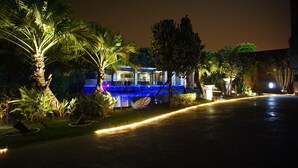 A well-lit outdoor area with a pool, palm trees, and a building with blue lighting. - All-Ur Boutique Motel - Ping-Tung Branch (Pingtung)