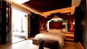 A spacious bedroom with a large bed, a bedside table, a nightstand, and a decorative stool. - All-Ur Boutique Motel - Ping-Tung Branch (Pingtung)