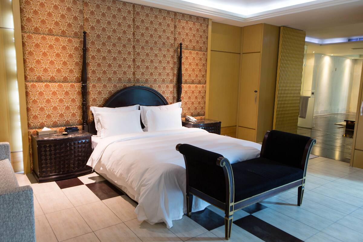 Een hotelkamer met een groot bed, een nachtkastje, een stoel en behang met een patroon.