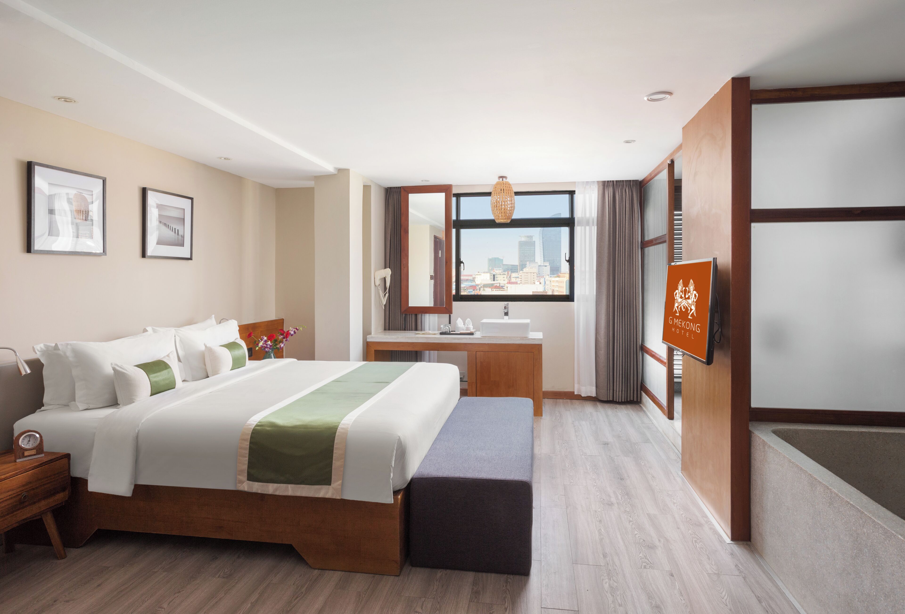 A hotel room with a bed, a desk, a bathroom, and a city view.
