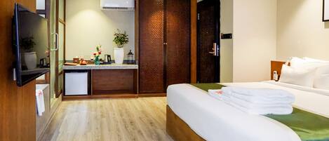 Una habitación de hotel con cama, kitchenette pequeño, armario y televisor.