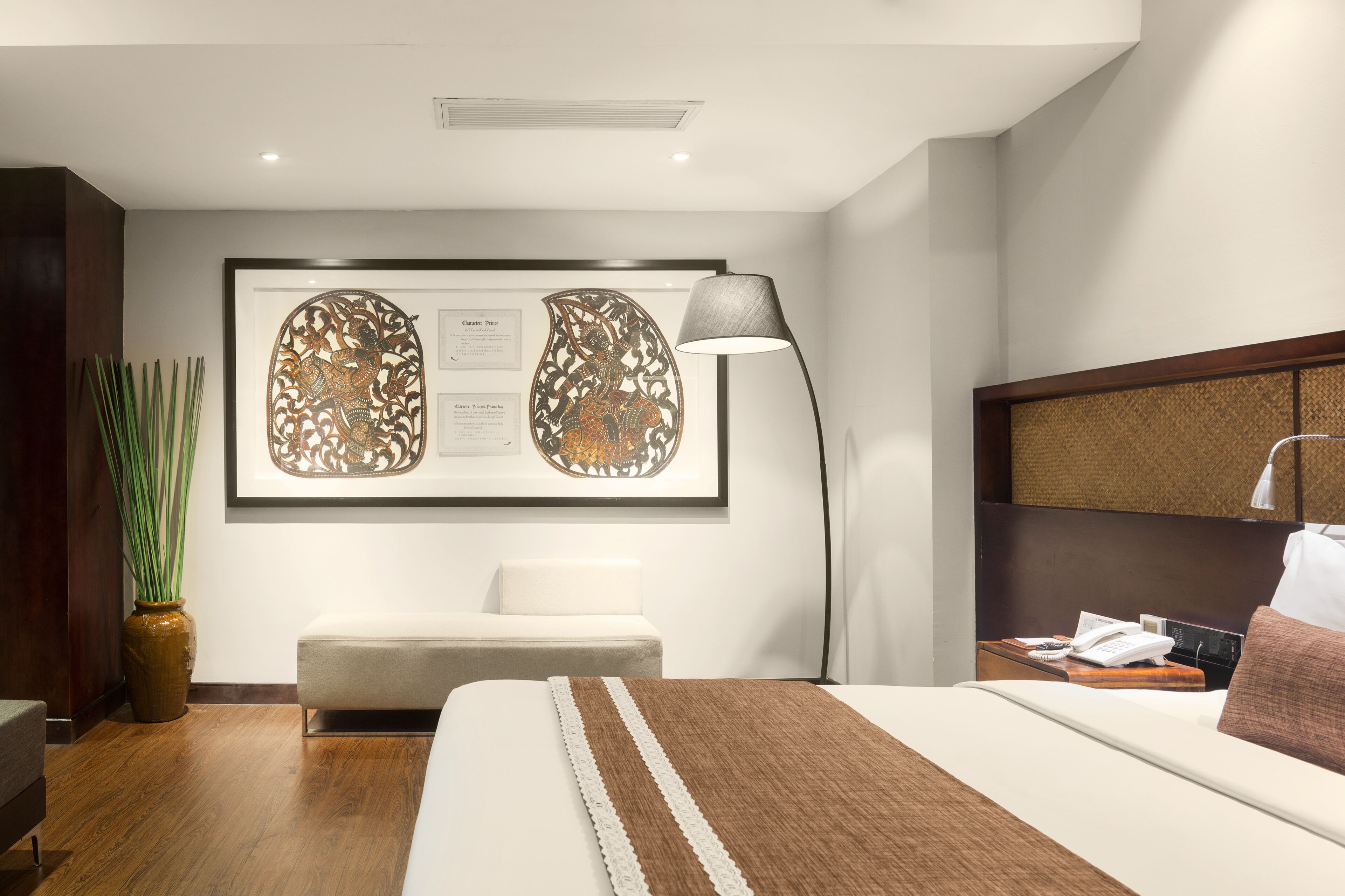 Ein Hotelzimmer mit Bett, Nachttisch, Lampe und einem gerahmten Kunstwerk an der Wand.