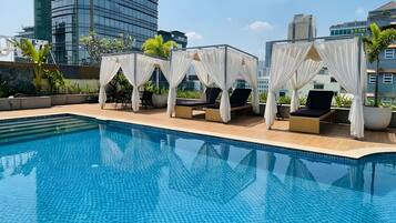 Una piscina al aire libre, sombrillas, sillones reclinables de piscina