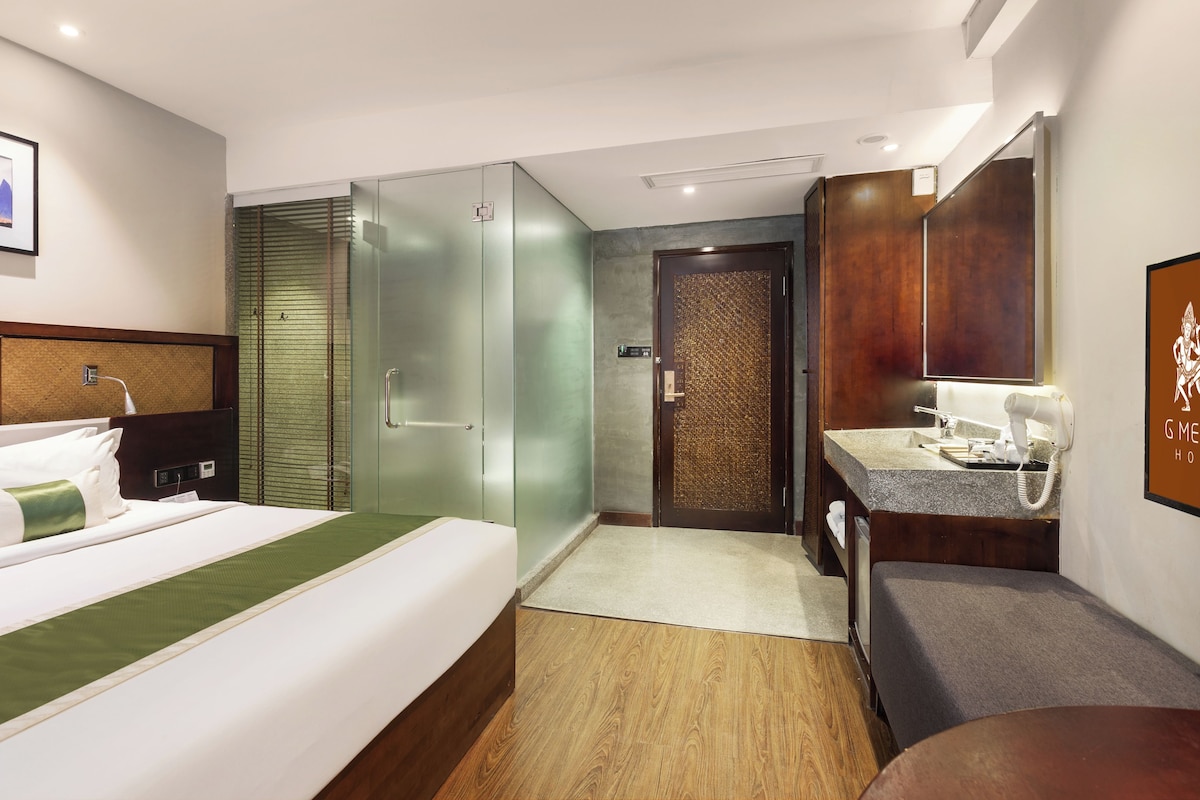 A hotel room with a bed, a bathroom with a mirror, and a shower area.