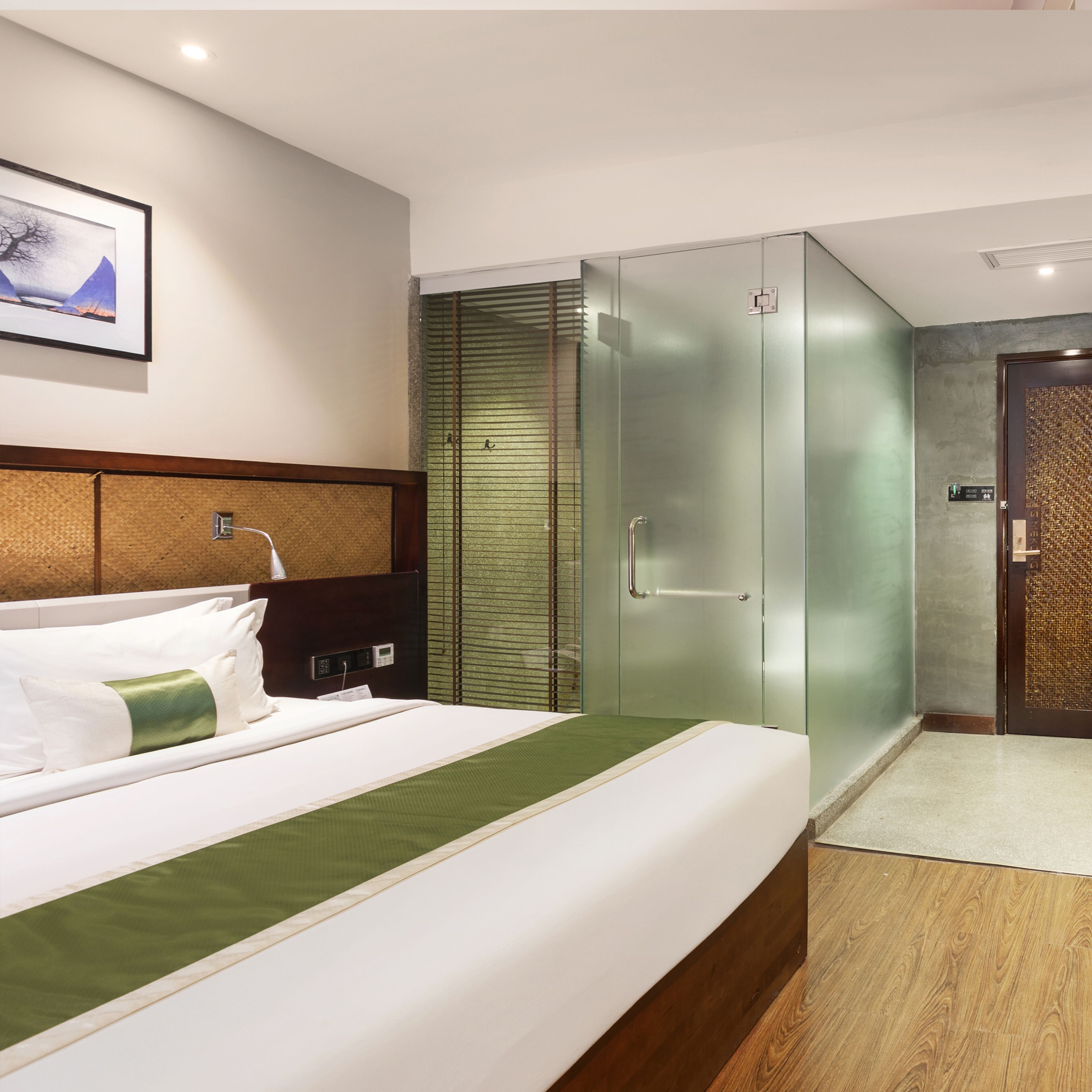 A hotel room with a bed, a wardrobe, a shower, and a wall-mounted artwork.
