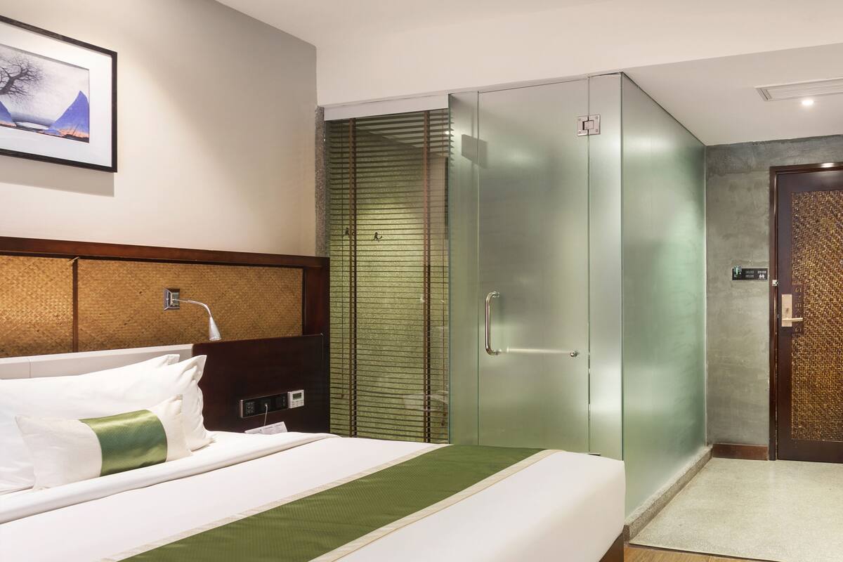 A hotel room with a bed, a wardrobe, a shower, and a wall-mounted artwork.