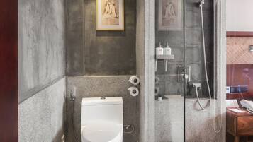 A bathroom with a toilet, a shower, and a framed picture on the wall.