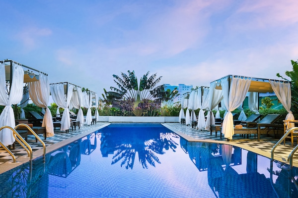 Una piscina al aire libre, sombrillas, sillones reclinables de piscina