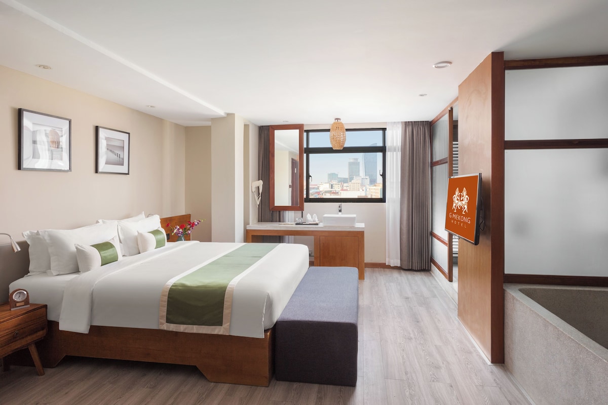 A hotel room with a bed, a desk, a bathroom, and a city view.