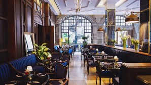 A restaurant with a high ceiling, arched windows, and a mix of seating arrangements including booths and tables. - The Gunawarman (Jakarta)