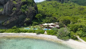 Un complexe hôtelier doté de plusieurs piscines, d’une plage et d’une végétation luxuriante.