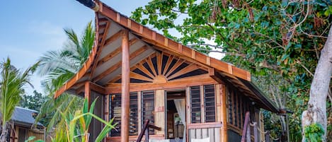 Una casa de madera con tragaluz, rodeada de vegetación tropical.