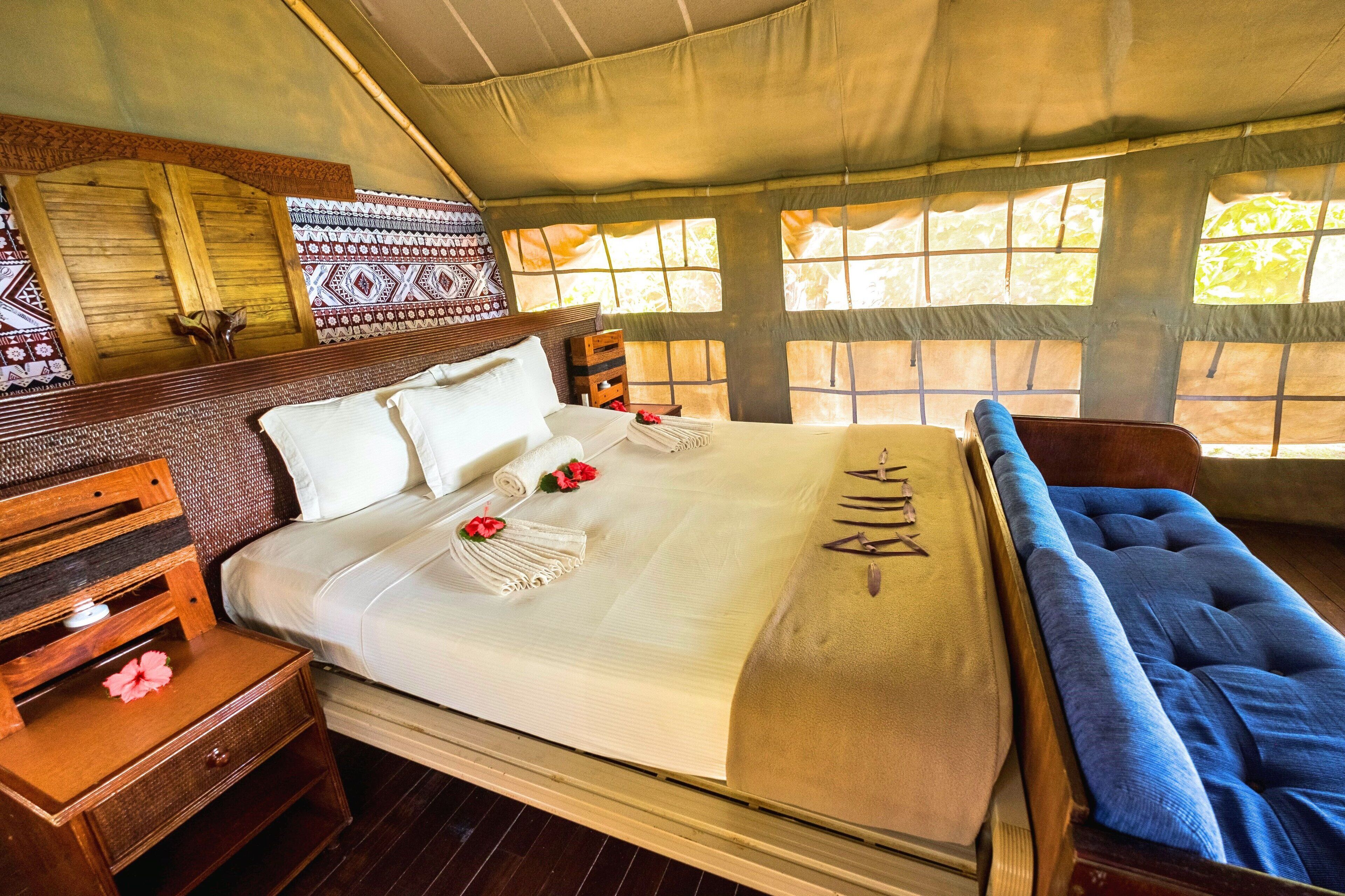 A bed with a white bedspread, a wooden headboard, and a blue upholstered bench.