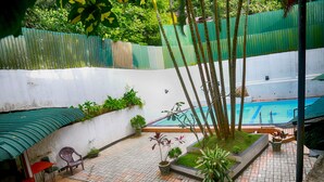 A courtyard with a swimming pool, potted plants, and outdoor seating. - Hotel Sunrich Kandy (Hedeniya)