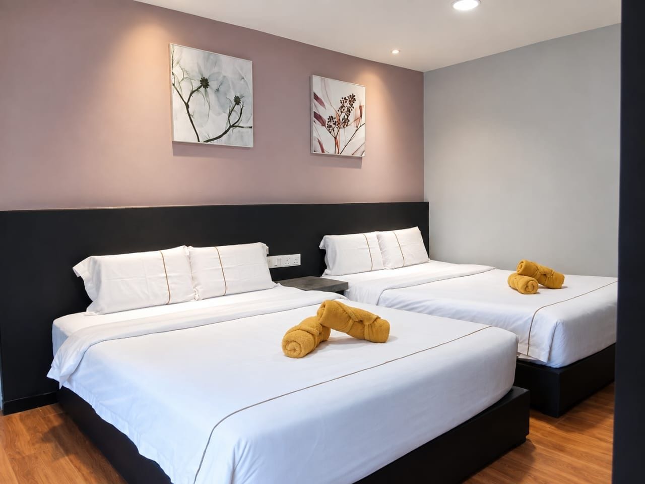 A hotel room with two beds, white bedding, and a pair of yellow towels.