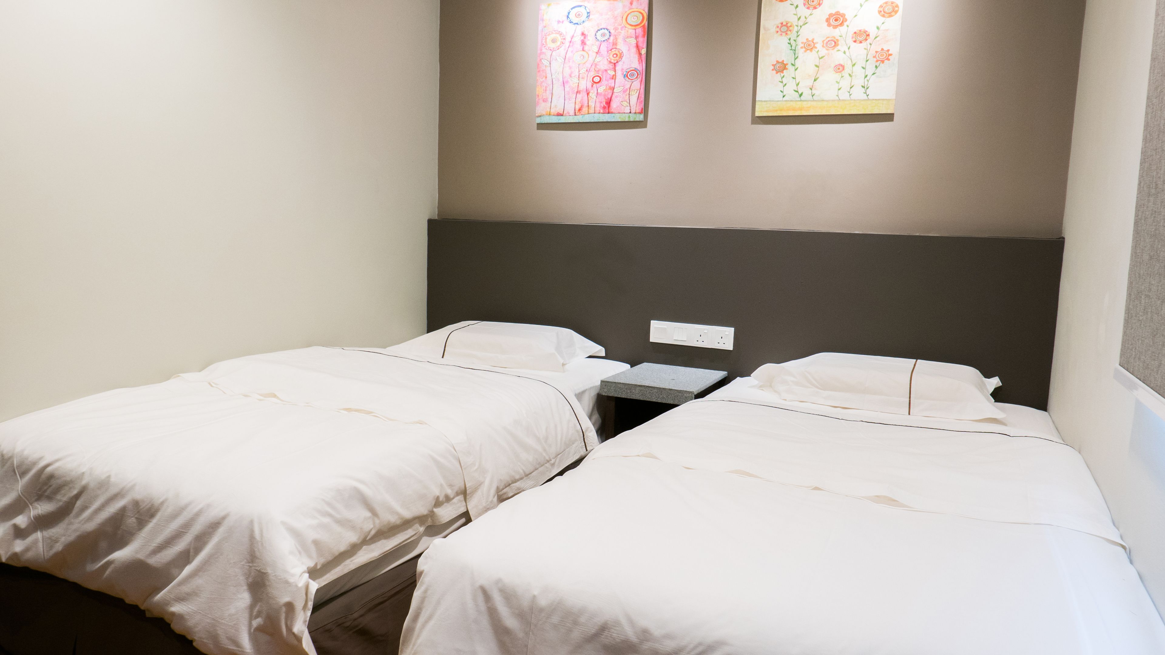A twin room with two single beds, a small bedside table, and a nightstand.