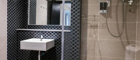 Un baño moderno con una pared perforada negra, un lavamanos blanco, un espejo y una ducha.