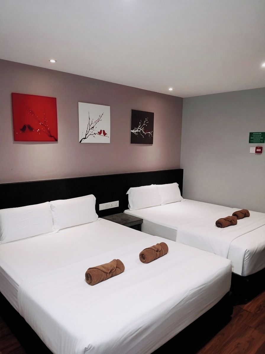 A hotel room with two beds, white bedding, and artwork on the walls.
