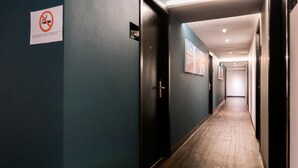 A hallway with a no-smoking sign, wooden doors, and framed pictures on the walls.