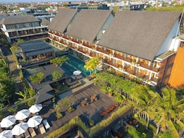 Un hotel con varios balcones, piscina y zonas de estar al aire libre.