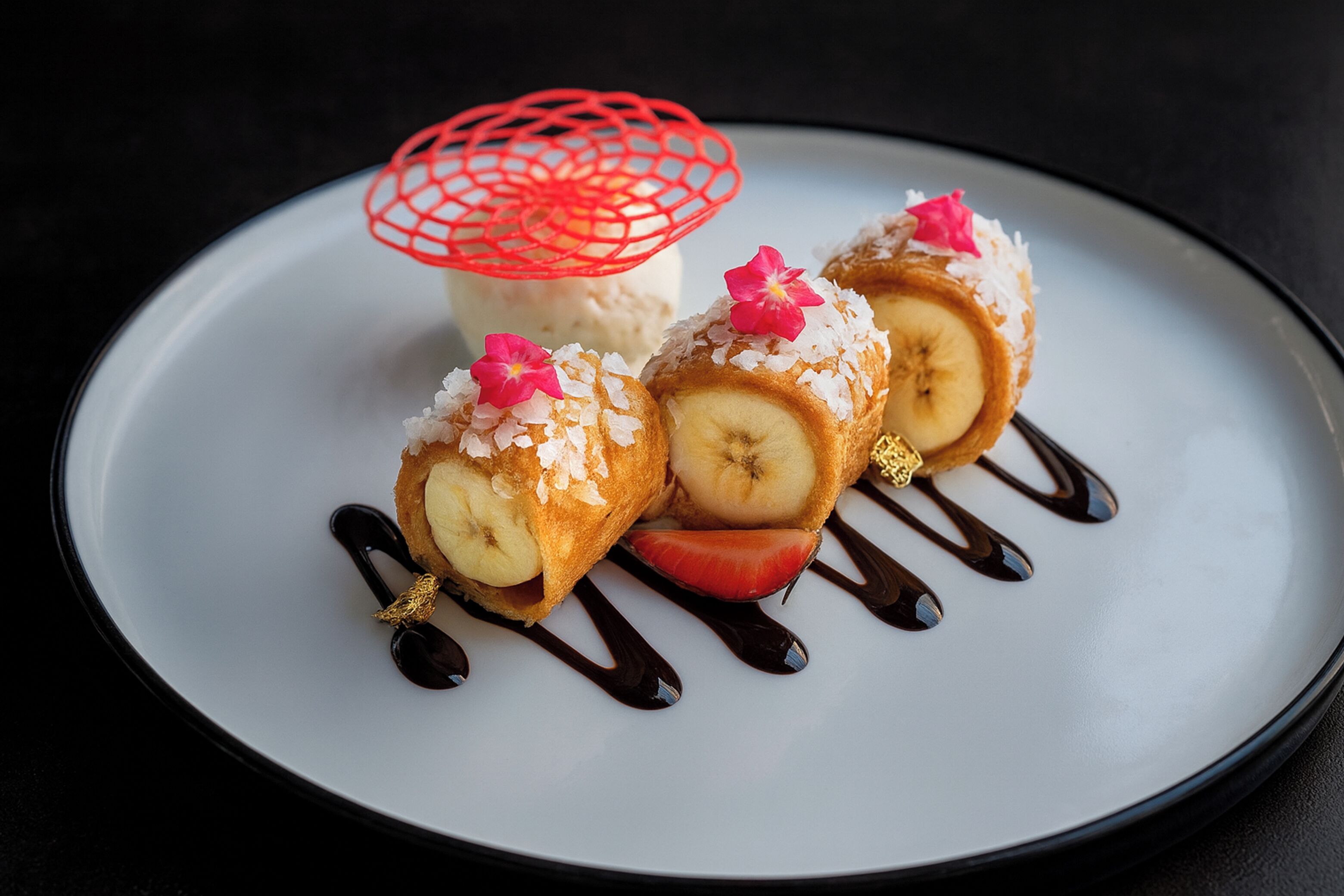 A dessert plate with banana slices, coconut, and chocolate drizzle.