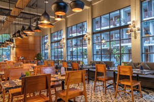 Un restaurant doté de mobilier en bois, d’un éclairage suspendu et de grandes fenêtres donnant sur des balcons.