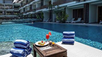 A poolside area with a wooden table, towels, and a plate of food.