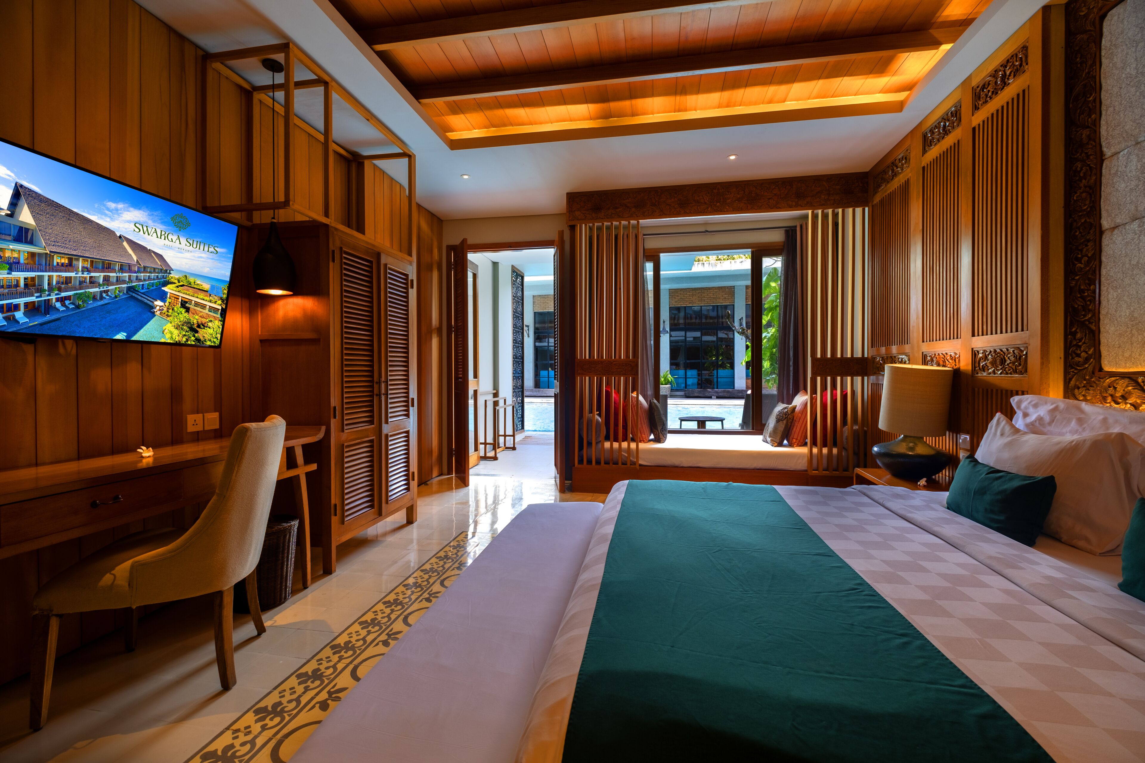 A hotel room with a large bed, a desk, a chair, a TV, and a view of the outdoors.