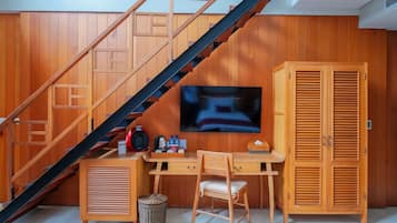 Una habitación con escritorio de madera, una silla, televisor, armario y una escalera.