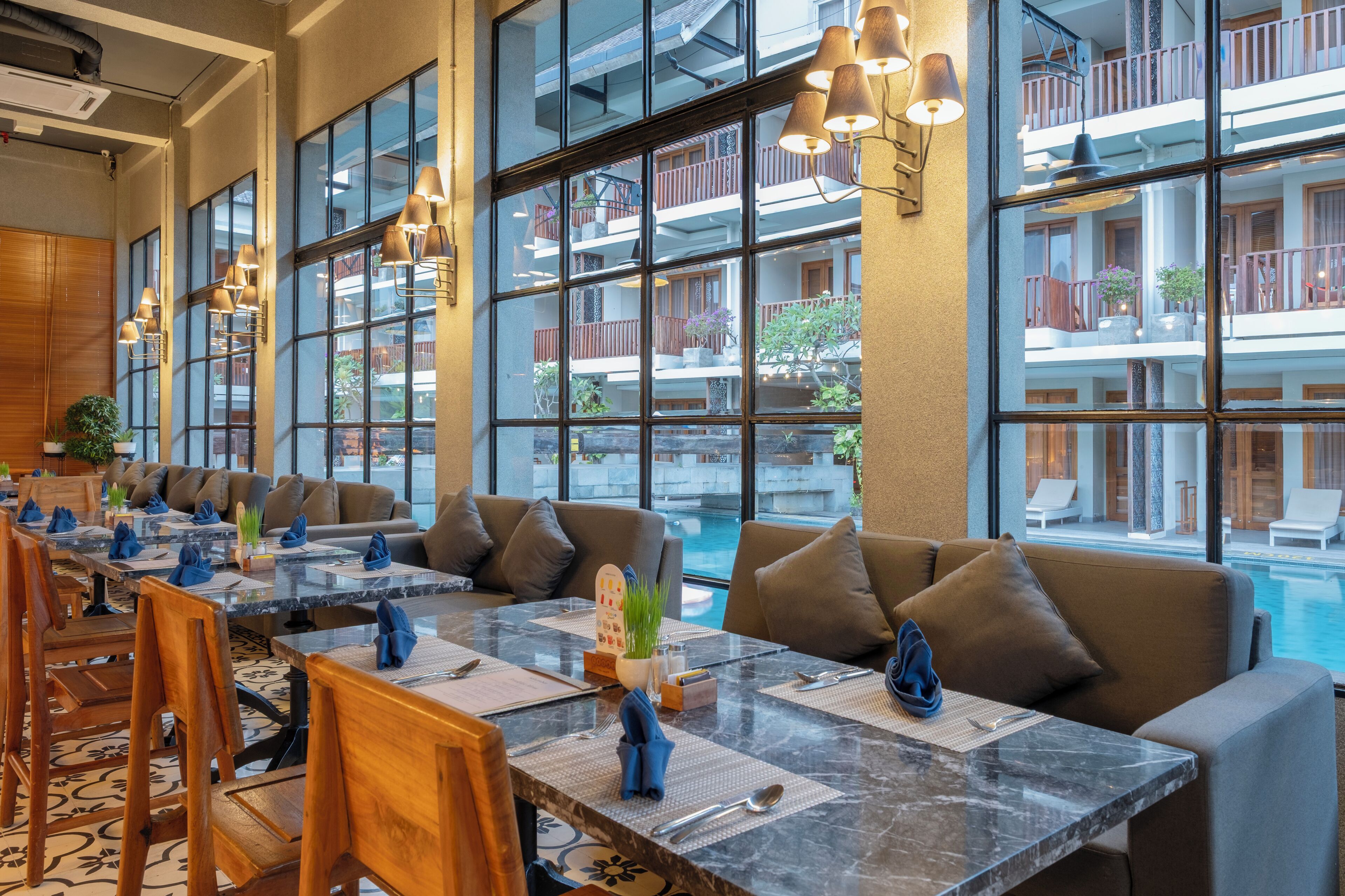 A dining area with a long table, multiple chairs, and a pool view.