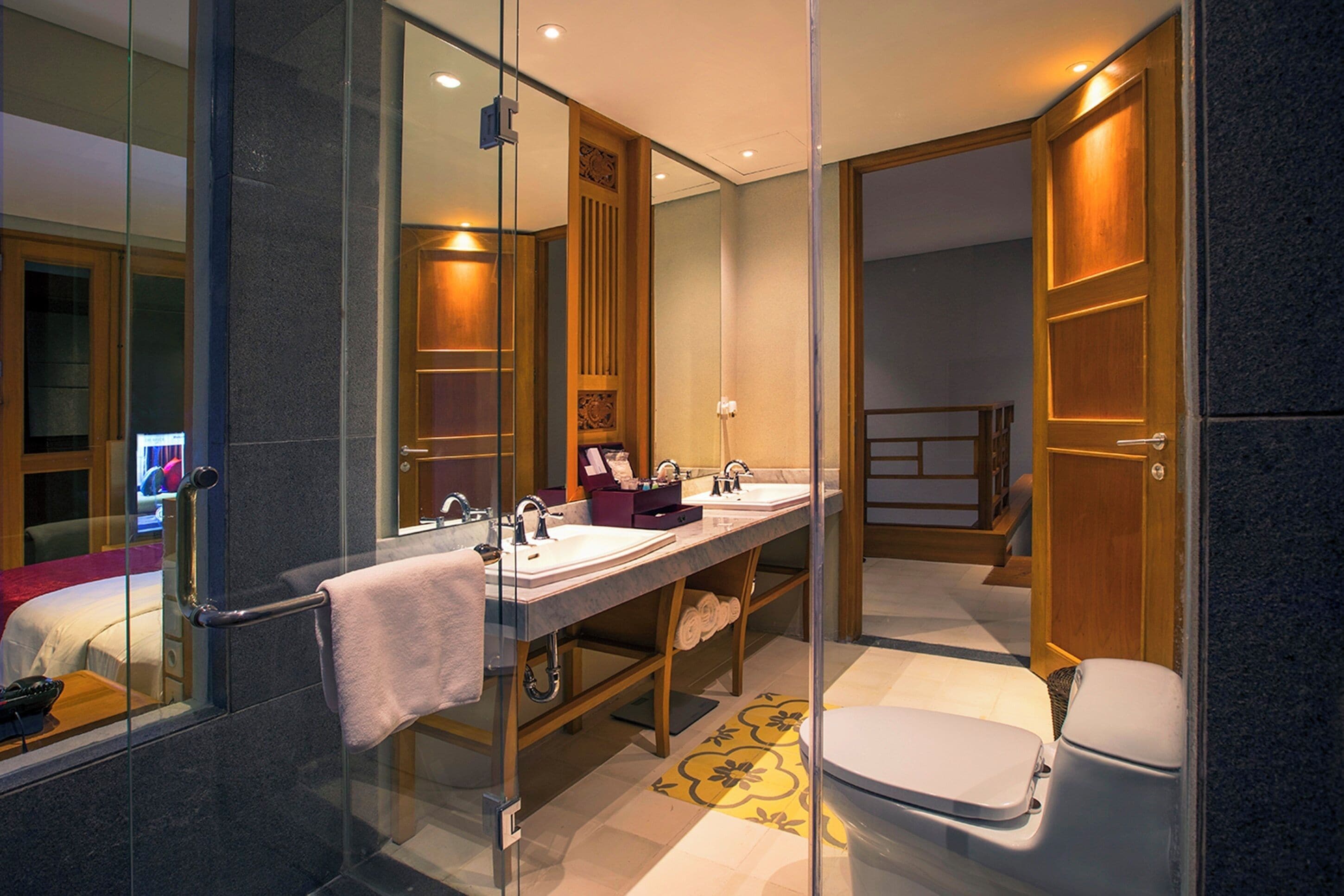 Ein modernes Badezimmer mit Glasabtrennung, einem doppelten Waschbecken, einer Toilette und einer Duschkabine.