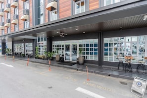 Un vestíbulo de hotel con diseño moderno, que cuenta con ventanas amplias y una zona de estar con mesas y sillas.