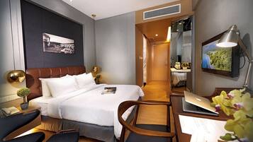 A modern hotel room with a bed, desk, chair, and a laptop.