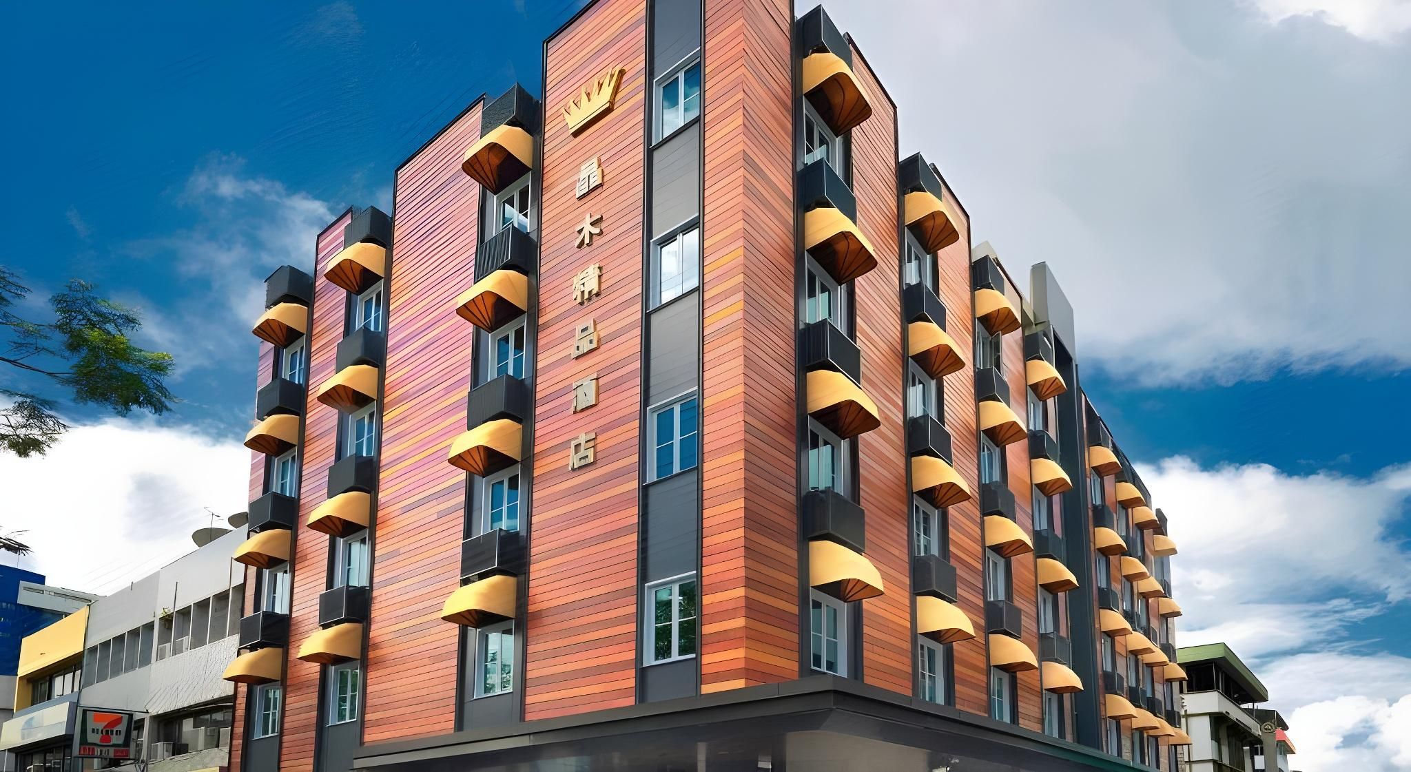 Ein mehrstöckiges Hotel mit modernem Design, mit Balkonen und gelben Markisen sowie einer auffälligen Schrifttafel an der Fassade.