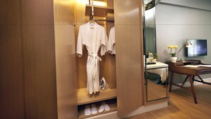 Ein Hotelzimmer mit Holzschrank, Spiegel, Schreibtisch mit Lampe und Fernseher.
