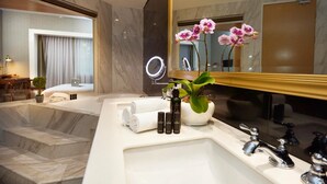 Ein modernes Badezimmer mit großem Spiegel, Marmorboden, einer Badewanne und einem Waschbecken mit Pflegeprodukten.