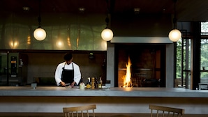 A chef preparing food at a counter with a fireplace in the background. - Hakone Retreat Före (Hakone)