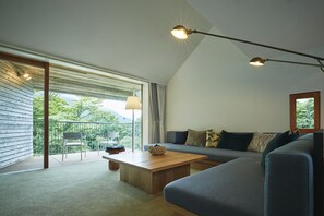 A modern living room with a sofa, a wooden coffee table, and a balcony with a chair. - Hakone Retreat Före (Hakone)
