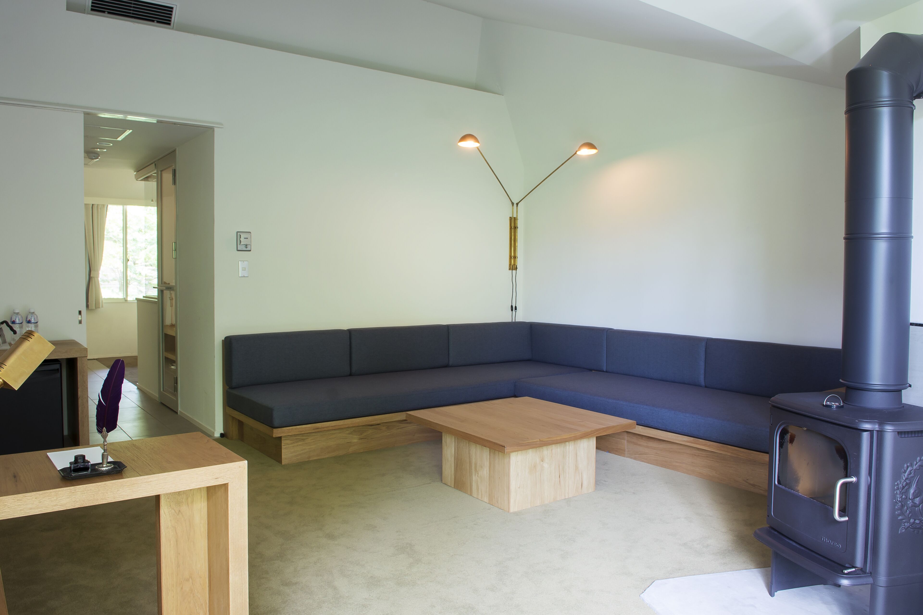 A modern living room with a sectional sofa, a wooden coffee table, and a black wood-burning stove.