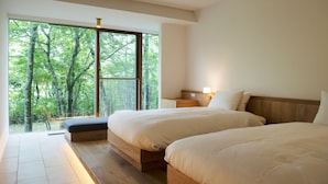 A bedroom with two beds, a large window, and a view of trees. - Hakone Retreat Före (Hakone)