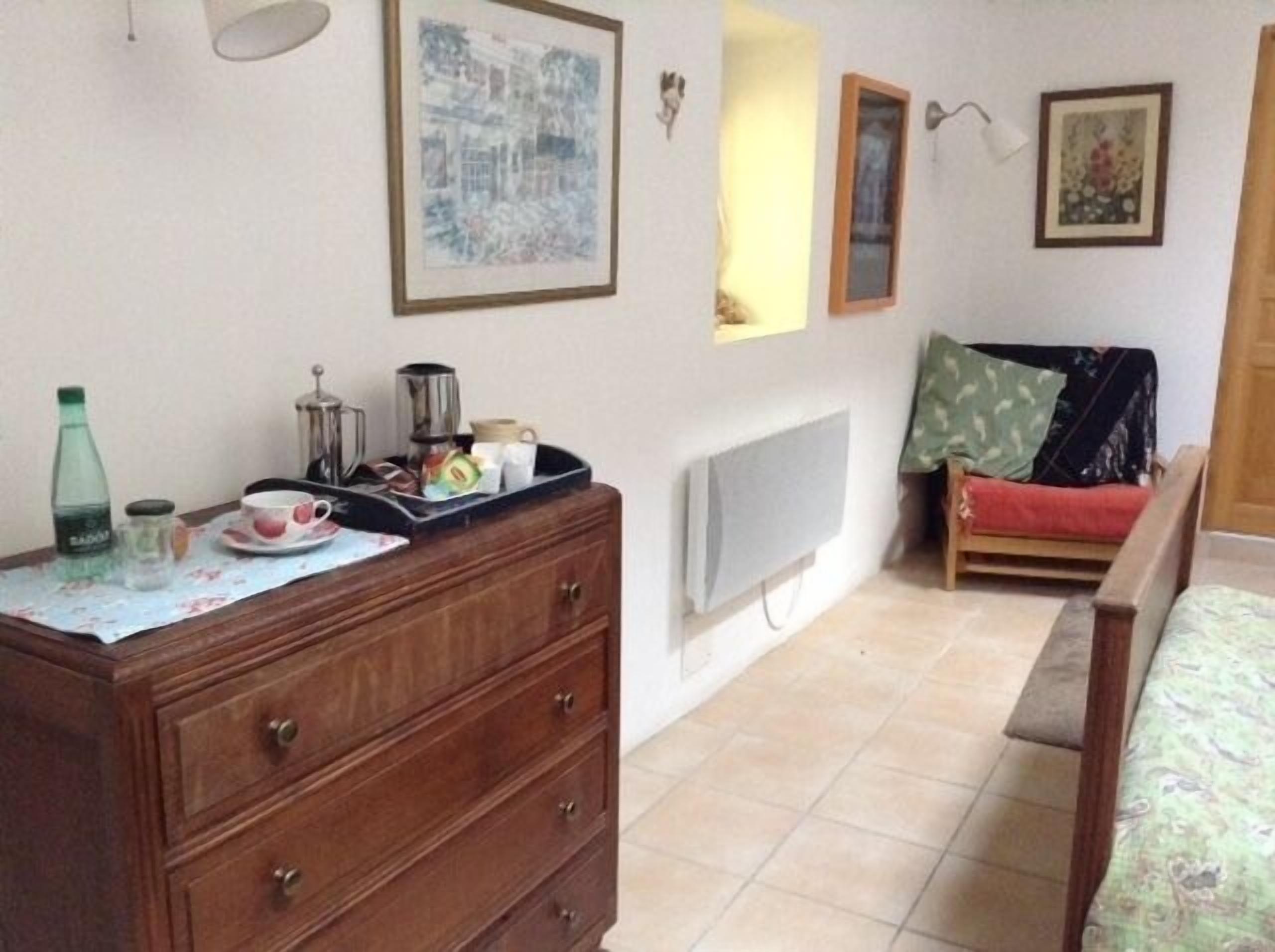 Un dormitorio con un aparador de madera, una cama, un televisor y una ventana.