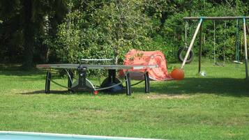 A pool area with a table tennis table, a swing set, and a covered seating area.