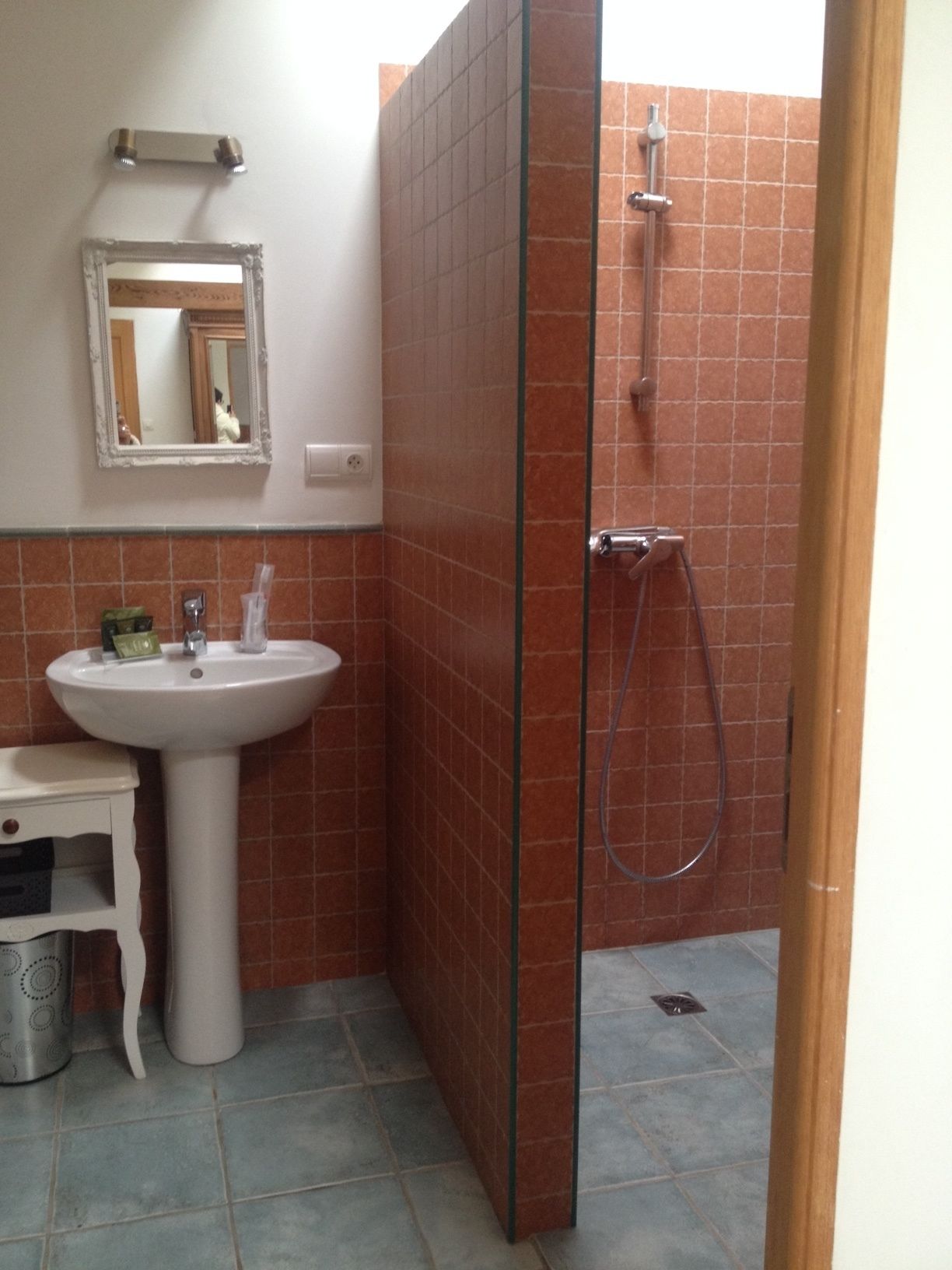 A bathroom with a white pedestal sink, a mirror, and a glass-enclosed shower area.