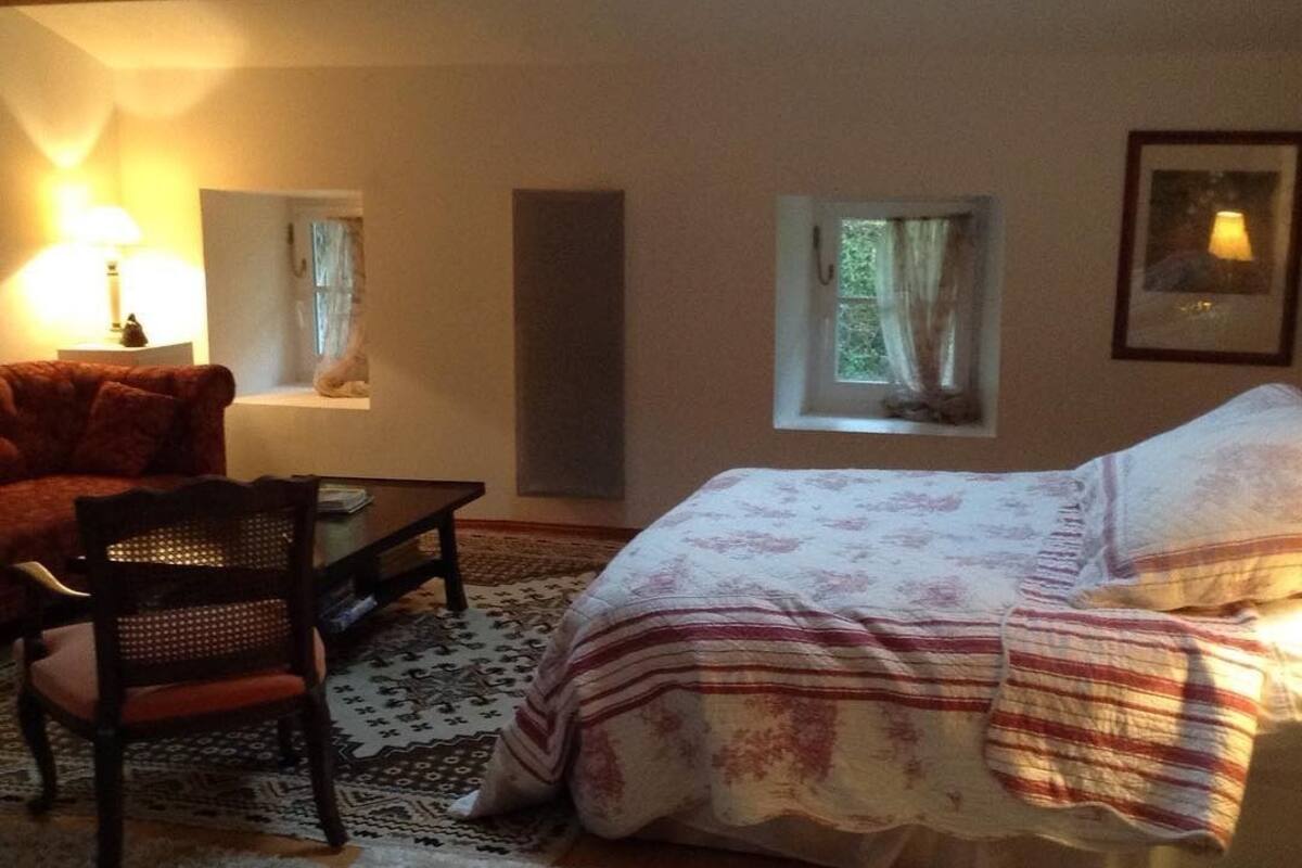 Ein gemütliches Zimmer mit Bett, Stuhl, Tisch und Lampe.