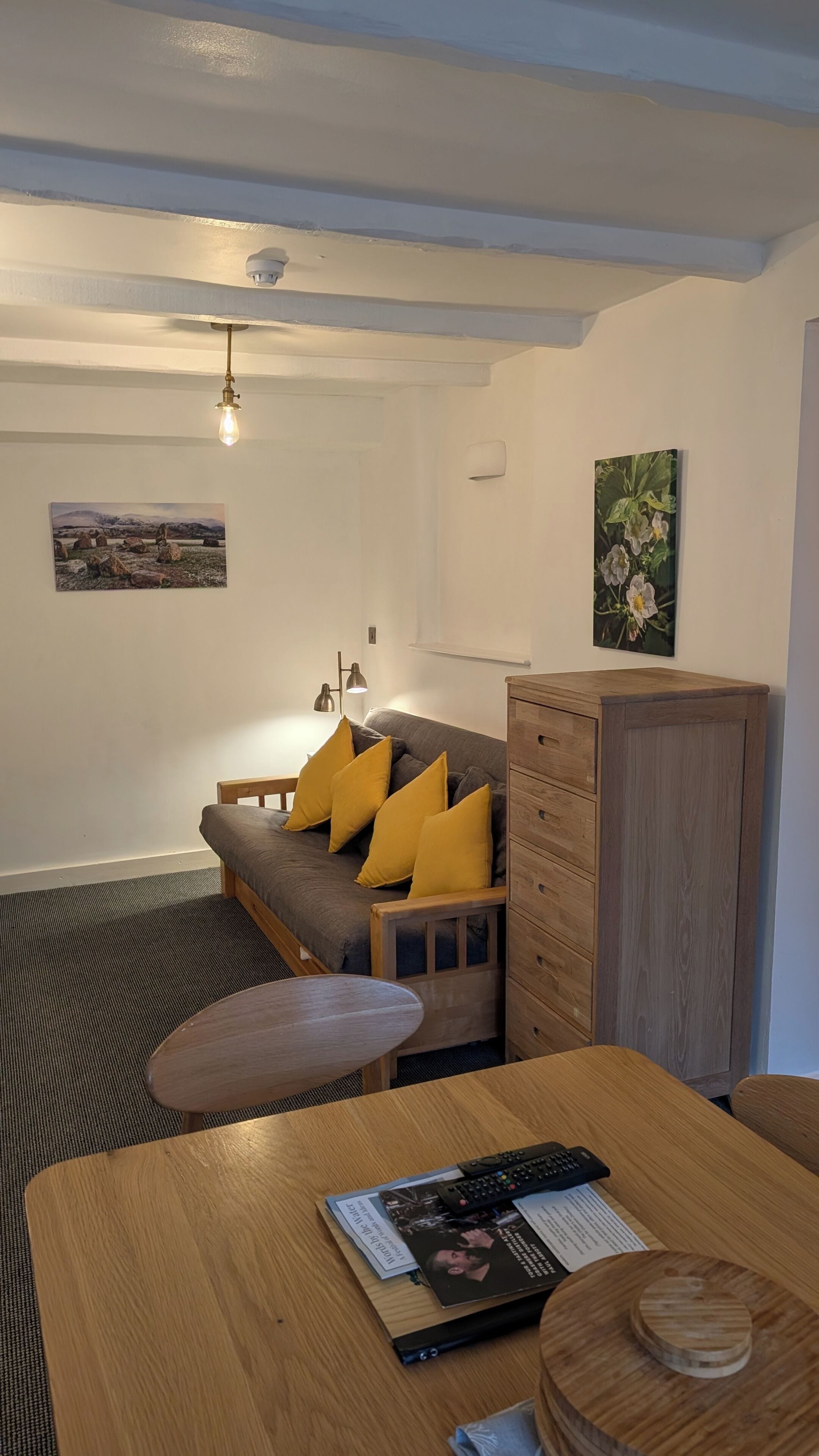 A cozy room with a sofa, wooden cabinet, and a table with a magazine.