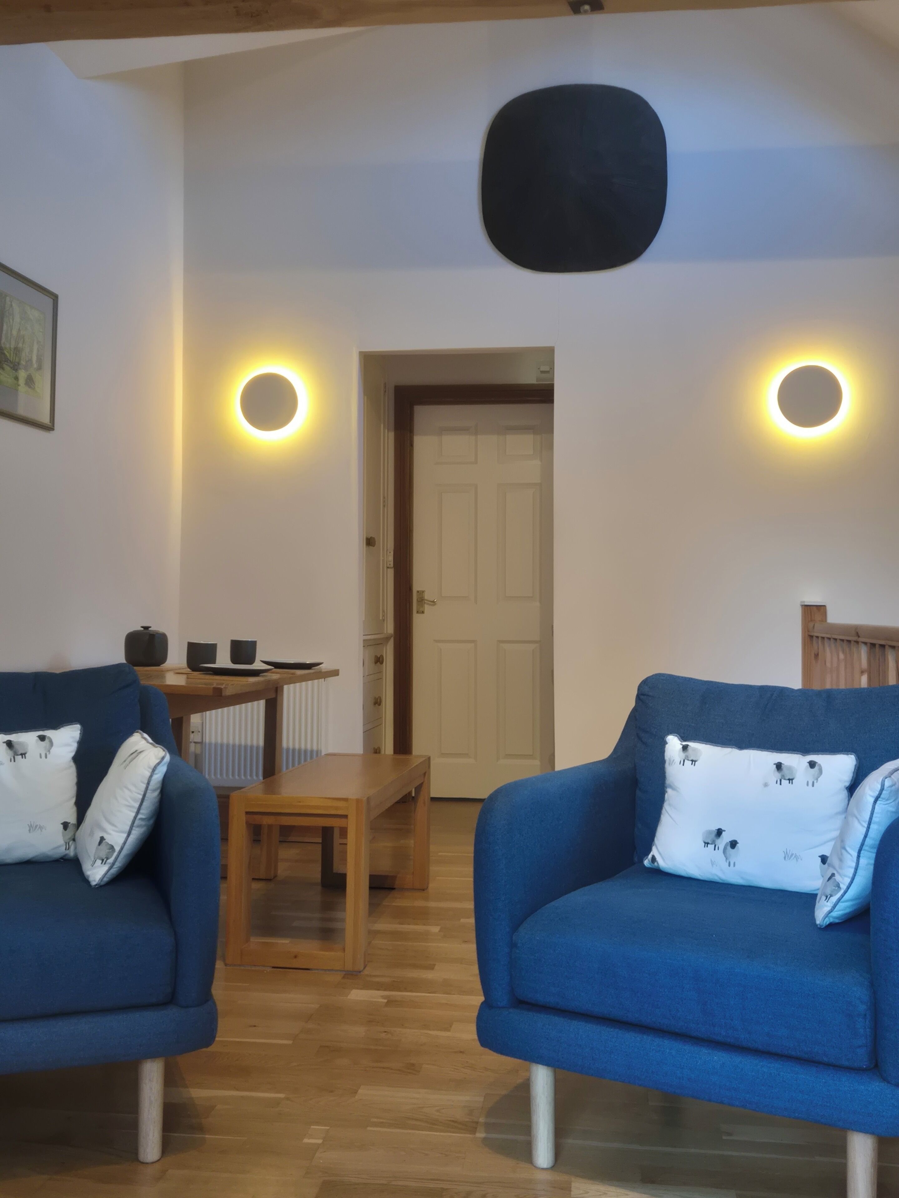 Una habitación con dos sofás azules, una mesa de madera y una puerta.