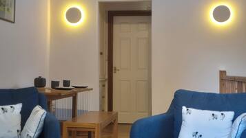 Una habitación con dos sofás azules, una mesa de madera y una puerta.